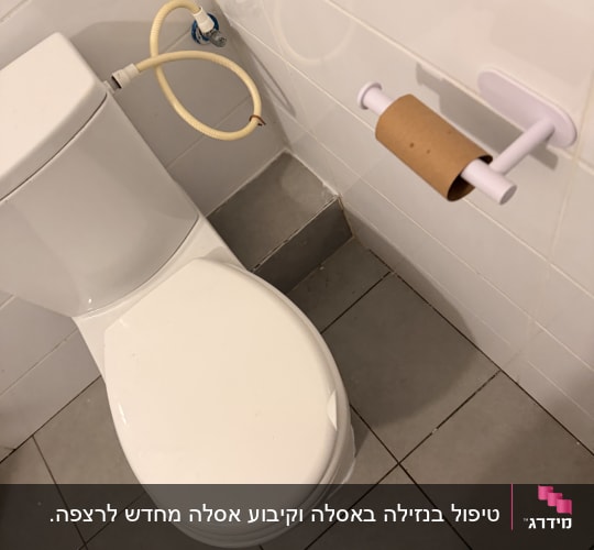 אסלה עם צינור מים ומתקן לנייר טואלט